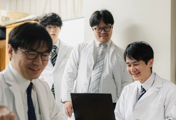 ノートパソコンを囲んで談笑する医師たち
