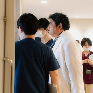 患者のそばで打ち合わせをする医療スタッフ